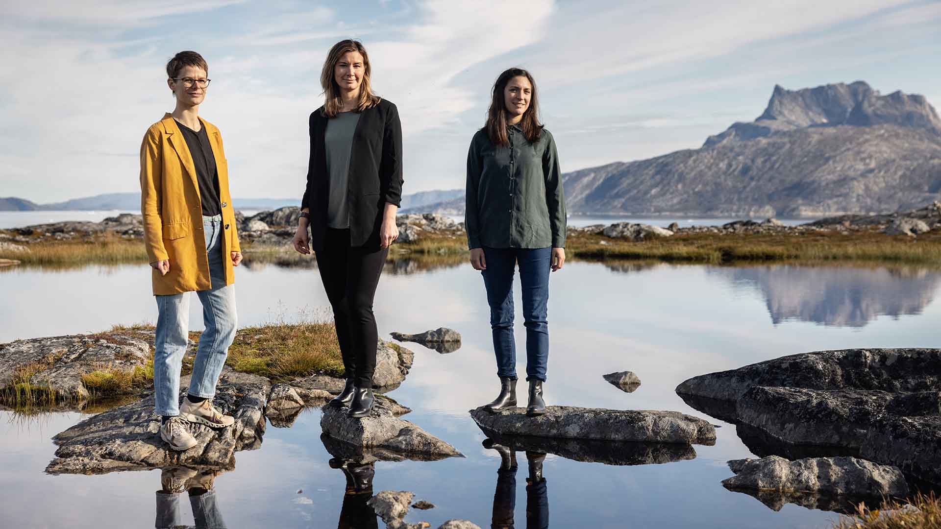 This image shows the secretariat of the Arctic Hub standing outside in front of the mountain Sermitisiaq. Anna-Sofie Skjervedal, Jula Maegaard-Hoffmann, Nicoline Larsen Arctic Hub Greenland Research