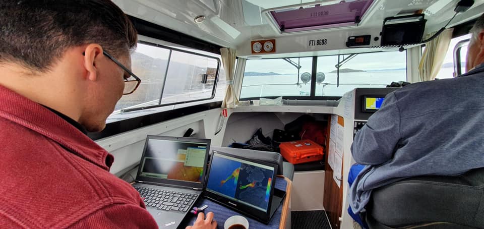A researcher is sitting in a boat with his computer